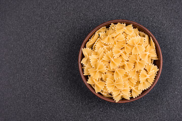 Farfalle or Bow Tie Pasta in bowl on gray background. Italian pasta. Copy space