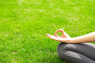 A woman practices yoga outdoors on the grass. Copy space