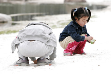 A boy and a girl squatting down playing with sand