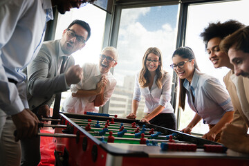 Business people having great time together. Colleagues playing table football in office.