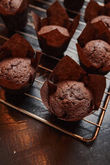 The process of making brown cupcakes on a metal grid, standing on a black wooden table. Cupcake in paper packaging.