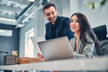 Smiling woman working together with bearded colleague at modern office