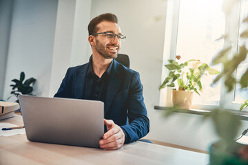 Handsome project manager with laptop in the cabinet