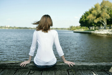 Fototapeta na wymiar A teenage girl spending time leisurely beside the lake