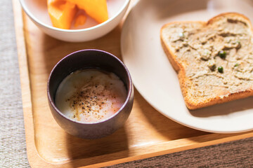 Chicken liver pate on bread with iced coffee, mango and soft boiled egg with seasoning sauce and ground pepper on wooden tray. Easy healthy breakfasts for your morning.