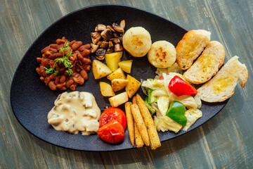 delicious red bean on the bread with potato and tomato,fried corn cobs with mushrooms on black plate vegan organic meal