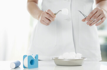 Female doctor picking up cotton swab with forceps