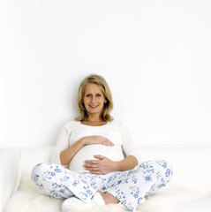 Naklejka premium Pregnant woman sitting on the couch touching her stomach