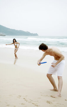 Couple playing Frisbee on the beach