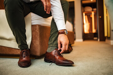 Businessman untying shoelaces on his shoes, low angle image, close-up.