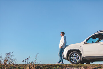 young adult man standing near car in sunglasses blue sky on background