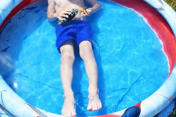 Happy boy child having fun at swimming pool and playing with toy shark on sunny summer day. Children playing and active leisure - swimming pool concept. 
