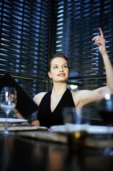 Fototapeta na wymiar Woman raising her hand to order her food in a restaurant