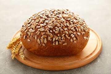 Wholegrain rye bread on a cutting board on grey background