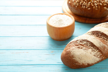 Delicious freshly baked brown bread on blue wooden background