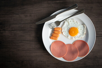 English breakfast, fried eggs, ham and filling on a wooden table