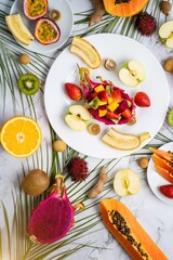 Exotic fruits and tropical leaves on table