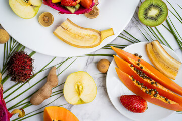 Exotic fruits and tropical leaves on table
