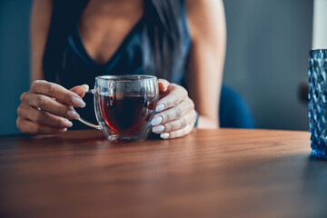 Woman hand holding cup of tea at the table
