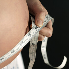 Pregnant woman measuring her stomach with tape measure