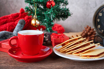 Red coffee latte cup with cracker with background gift boxes decorate under christmas tree, christmas festival concept.