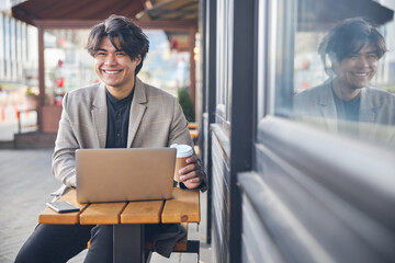 Joyful young man using notebook in outdoor cafe