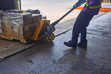 Worker unloading shipment carton boxes and goods on wooden pallet by forklift  from container truck...