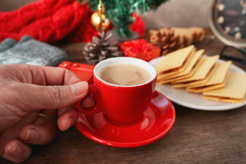 Hand hold red coffee cup wirh snack on the table