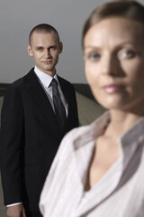 Businessman looking at camera with businesswoman in the foreground