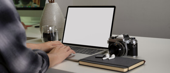 Female photographer working on modern office desk with mock-up tablet, camera and supplies