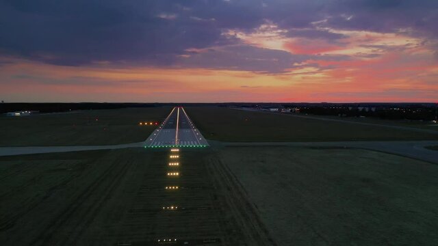 Aerial view on empty airport runaway with markings for landings and all navigation lights (ILS Cat II) on at the colorful sunset, clear for airplane landing or taking off in Wroclaw airport