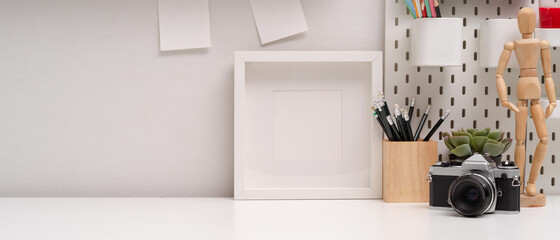 Simple workspace with copy space, mock-up frame, camera, stationery and decorations