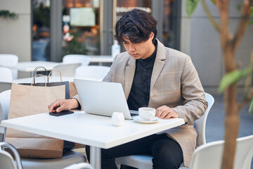 Handsome young man using laptop in outdoor cafe