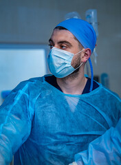 Fototapeta na wymiar Portrait of doctor in scrubs. Surgery room background. Doctor in medical mask. Close up shot.