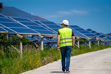 The concept of green new energy. Engineer at solar plant. Walking to the solar panels.