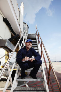 Mechanic Standing On Stairs Of Passenger Boarding Bridge