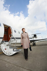 Businesswoman walking away from private jet after landing on runway
