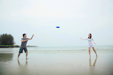 Man and woman playing with flying disc on the beach