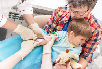 Hands of nurses is collecting a blood from a vein from the kid.