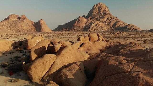 Spitzkoppe and its arch, moving-forward view of an arid landscape composed of rocky mountains, during a sunny day in Namibia, famous travel destination