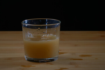 Filling pear juice in a glass cup on a wooden surface