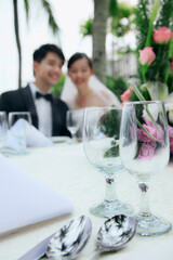 Bride and groom at their wedding reception, focus on foreground