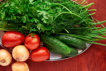 healthy food - fresh vegetables and greens on a wooden background, greens, onion and tomatoes