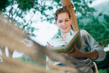 Woman lying in hammock writing diary