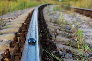 Black toy car on the old railway tracks as on the road. Concept of speed, auto racing, risk, elegance, car industry. Selective focus.