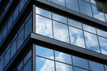 facade of a modern building on a bright Sunny day, blue sky and clouds reflecting in a glass, beautiful exterior of the new building