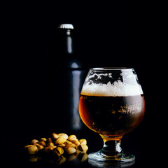 Beer mug, bottle and nuts on a dark background