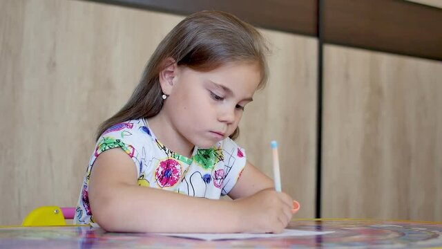 Happy little girl or cute primary child school child painting or writening on paper. Children elementary education concept.