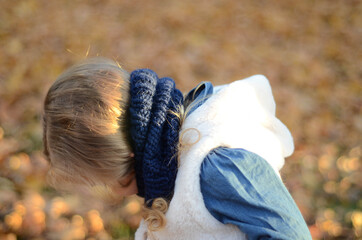 Picture of a smiling blonde toddler girl playing outside wearing the knitted snood