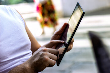 Male hand touching screen tablet close-up. Online shopping. Young man with tablet computer in cafe shop. Business, technology, finger is shown up to the screen of the tablet. Copy-space.